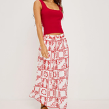 Woman wearing a red top and white patterned skirt on a white background