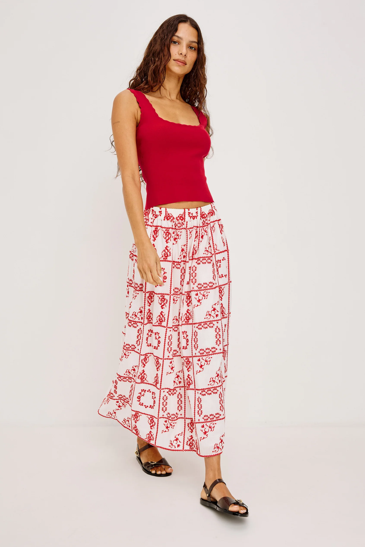 Woman wearing a red top and white patterned skirt on a white background