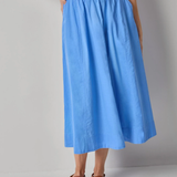 Person wearing a blue skirt and white top on a gray background