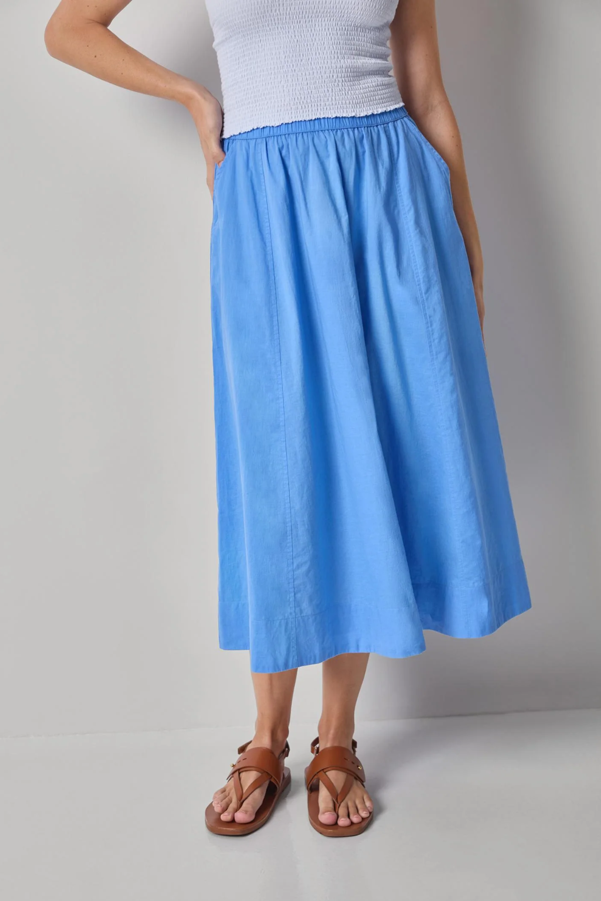 Person wearing a blue skirt and white top on a gray background