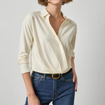 Woman wearing a cream blouse and blue jeans on a plain background