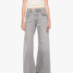 A model wearing light gray wide-leg denim jeans, a cream ribbed tank top, and black pointed-toe heels, standing against a plain white studio background.