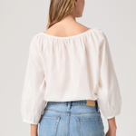 Woman wearing a white blouse and blue jeans on a plain background