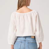 Woman wearing a white blouse and blue jeans on a plain background
