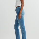 Person wearing light blue jeans and a white top on a plain background