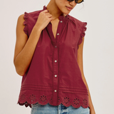 Woman wearing a burgundy sleeveless top with lace details and blue jeans on a white background