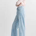 Person wearing light blue jeans and a pink shirt on a plain background