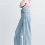 Person wearing light blue jeans and a pink shirt on a plain background