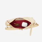 An open cream-colored leather clutch bag with gold-tone hardware, showing a deep burgundy red interior lining. Inside, a gold key and a white wireless earbud case are visible.