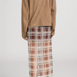 Person wearing a brown jacket and plaid skirt on a plain background