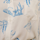 Close-up of a shirt with blue western-themed graphics on a white background