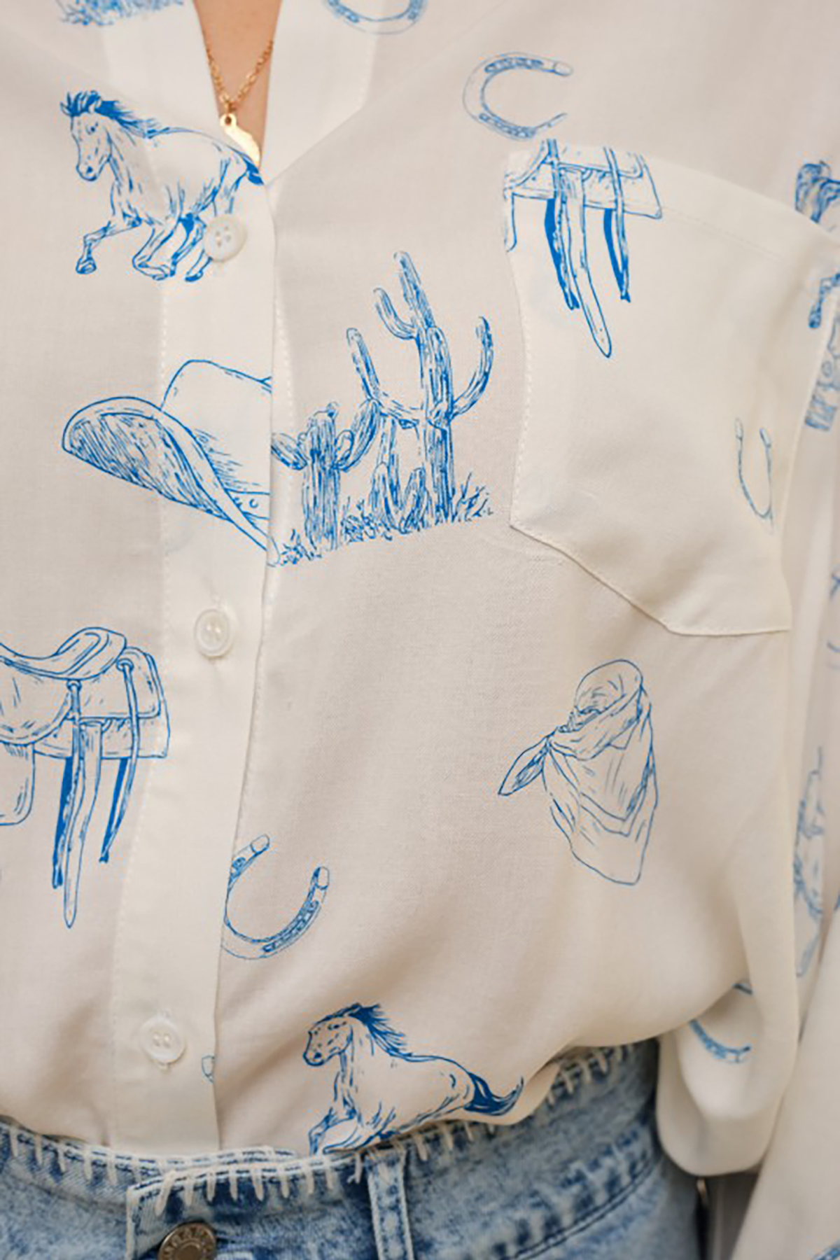 Close-up of a shirt with blue western-themed graphics on a white background