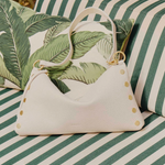 White handbag with green leaf pattern on a striped green and white surface