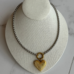 Mixed metal heart necklace on marble floor.