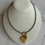 Mixed metal heart necklace on marble floor.