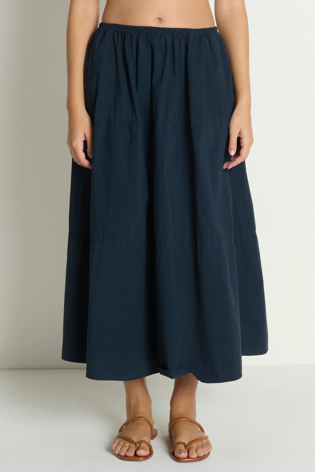 Person wearing a navy blue skirt on a plain background