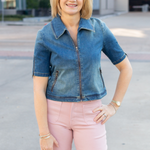 Woman wearing a denim jacket and pink pants standing outdoors.
