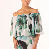 Woman wearing a green and white floral off-shoulder dress on a white background