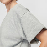 Gray t-shirt worn by a person on a plain background