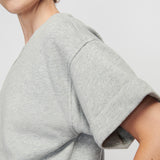 Gray t-shirt worn by a person on a plain background