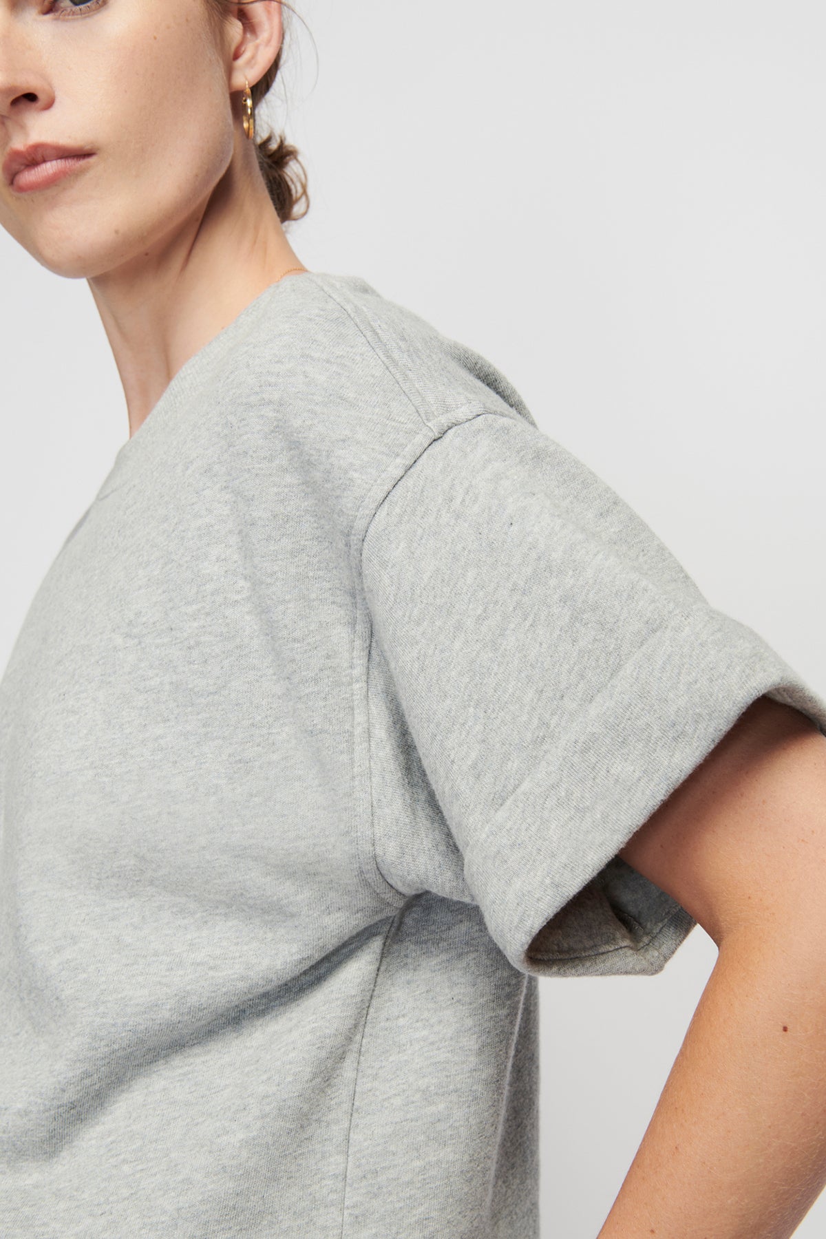 Gray t-shirt worn by a person on a plain background