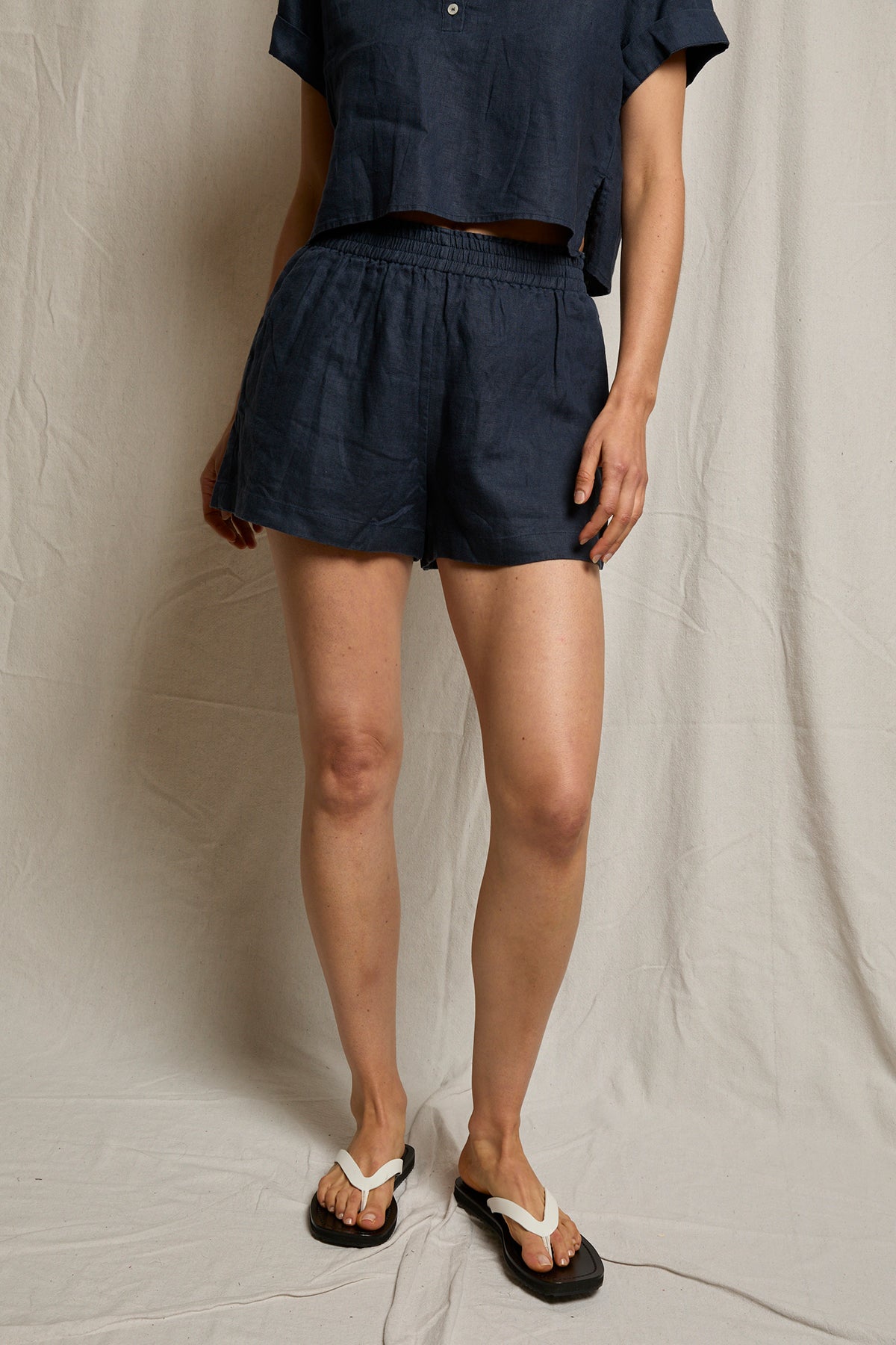 Person wearing navy shorts and a dark shirt against a plain background