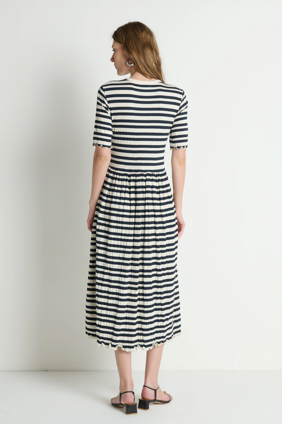 Woman wearing a black and white striped dress on a plain background