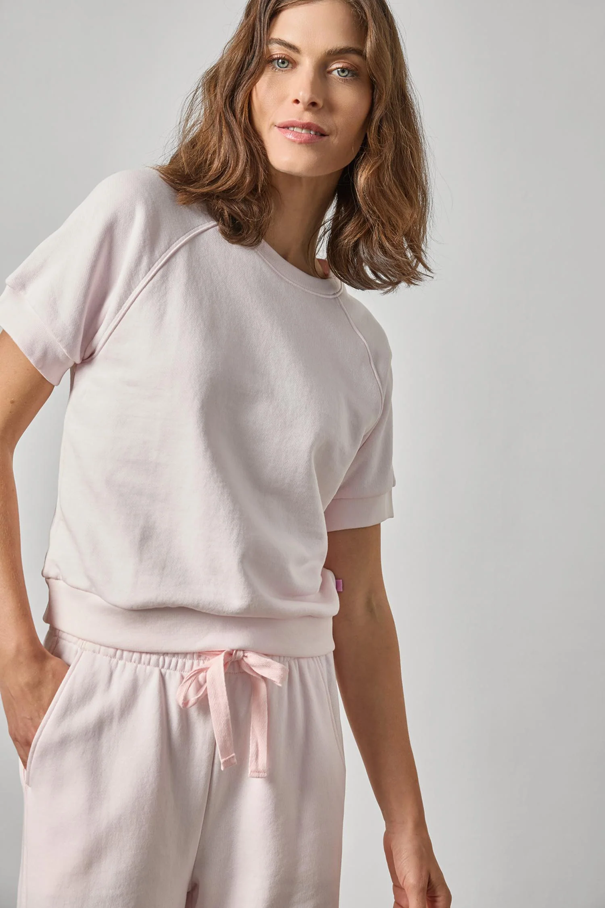 Woman wearing a light pink outfit on a plain background