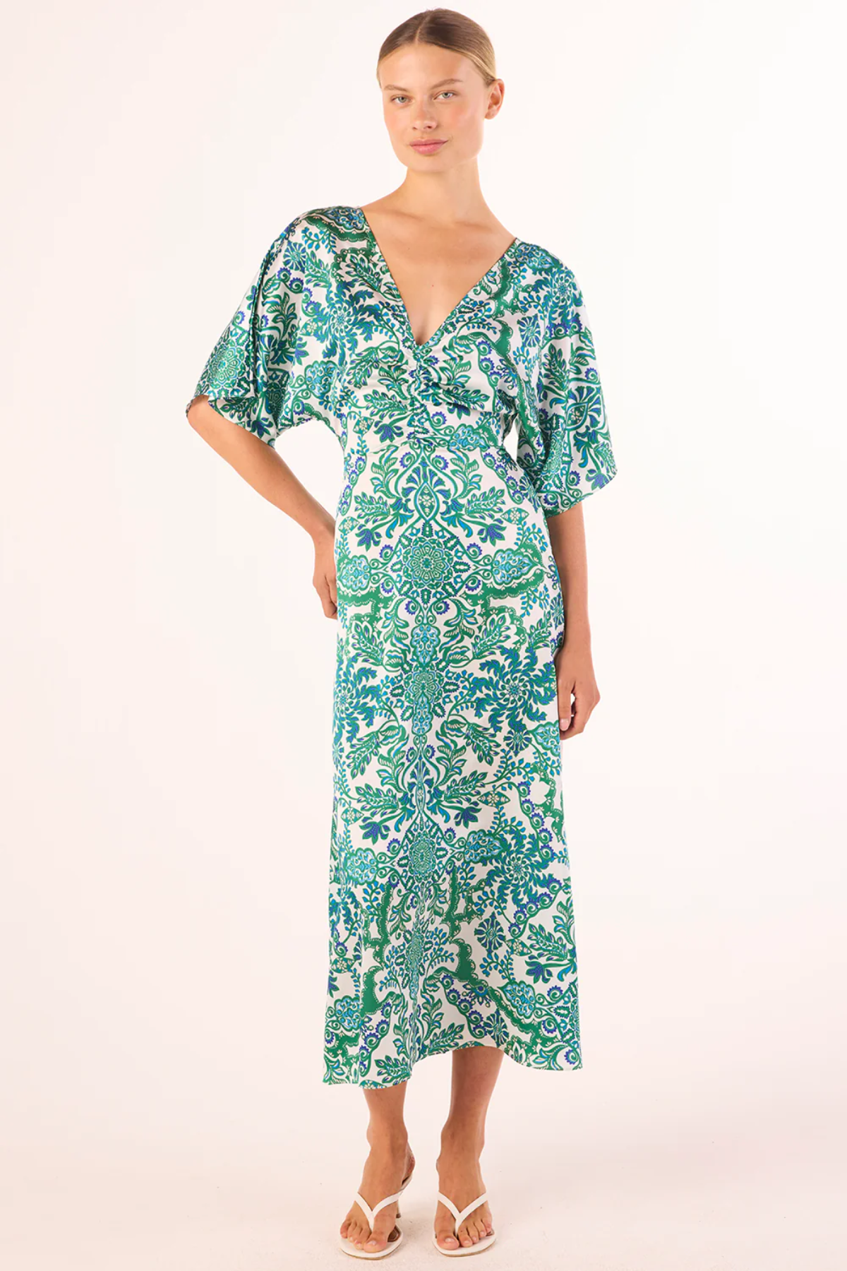 Woman wearing a green and white patterned dress on a white background