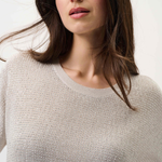 Woman wearing a beige sweater against a white background