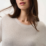 Woman wearing a beige sweater against a white background