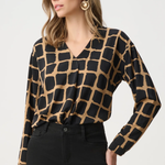 Woman wearing black and gold patterned top against a white background