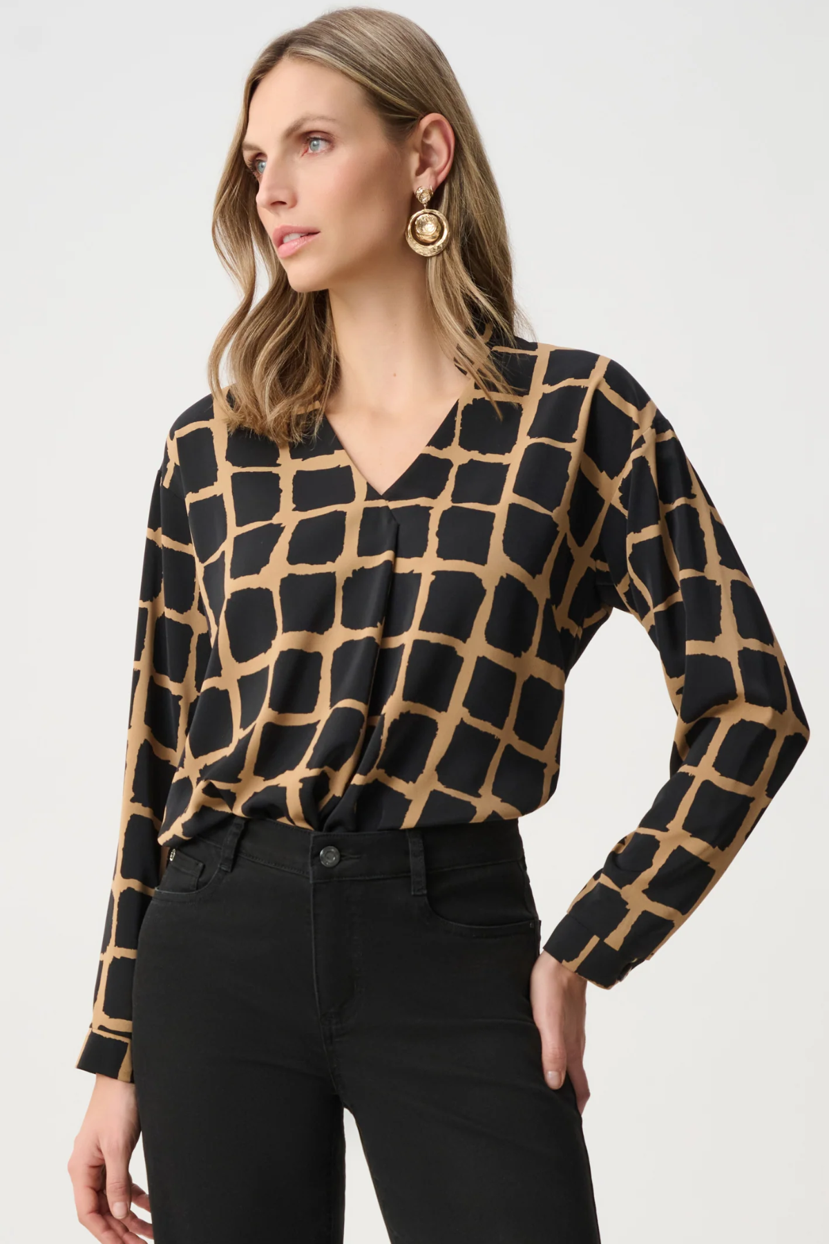 Woman wearing black and gold patterned top against a white background