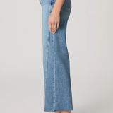 Person wearing light blue jeans and white sneakers on a plain background