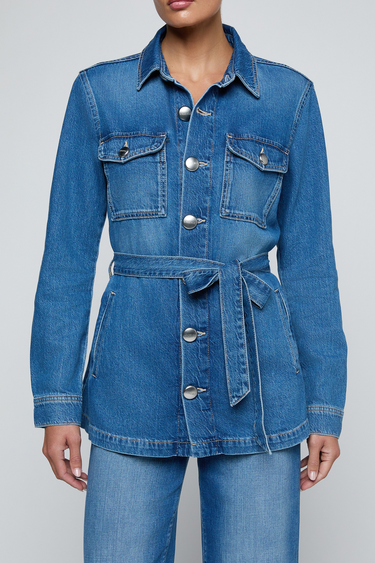 Model wearing a blue denim safari jacket with utility pockets and a button-front design.