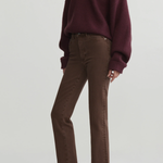 A model wearing a dark burgundy knit V-neck sweater, brown straight-leg jeans, and black pointed-toe flats, photographed against a light gray studio background.