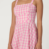 Woman wearing a pink and white checkered dress on a white background