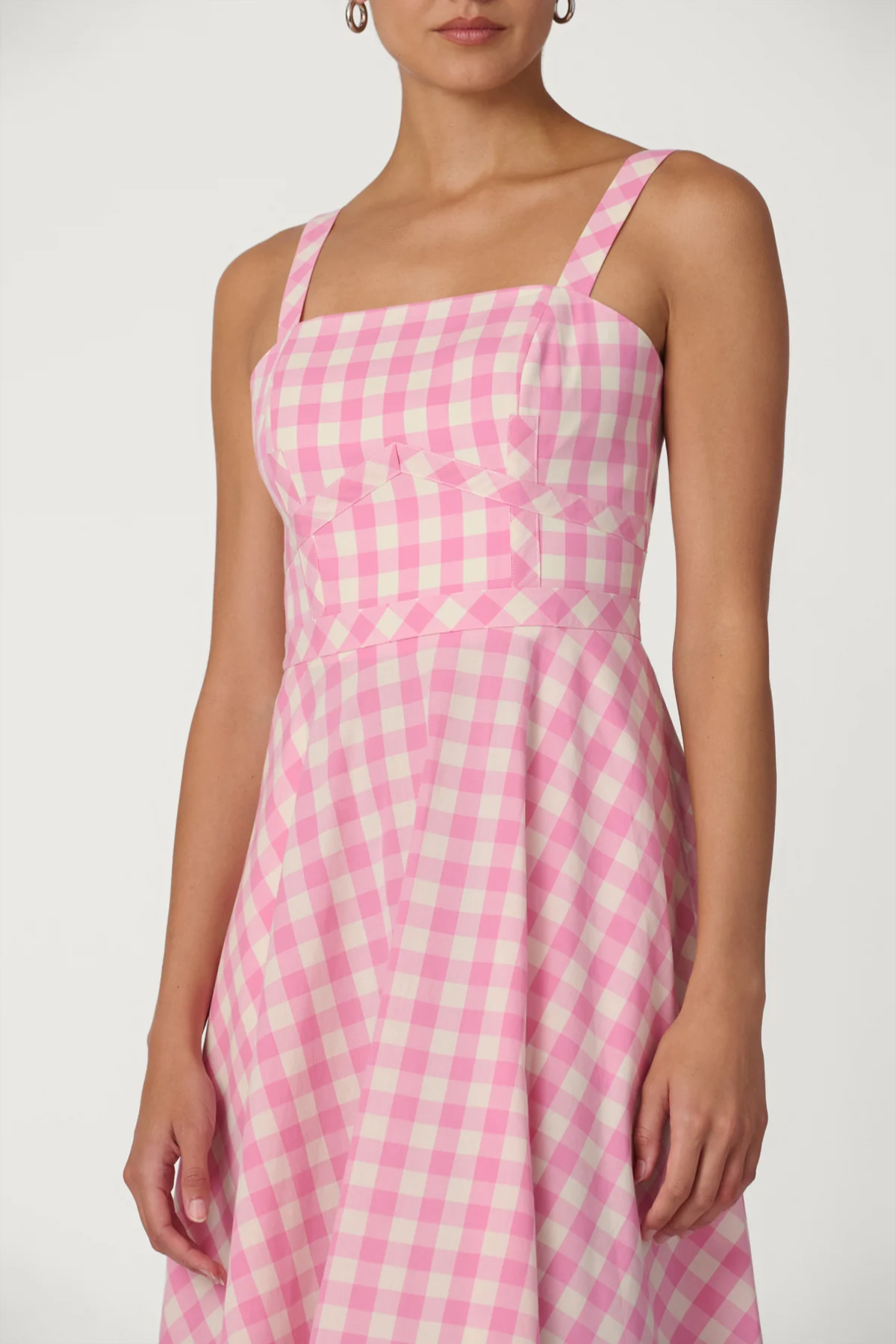 Woman wearing a pink and white checkered dress on a white background
