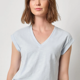 Woman wearing a light blue t-shirt against a plain background