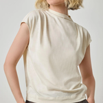 Woman wearing a beige sleeveless top against a plain background