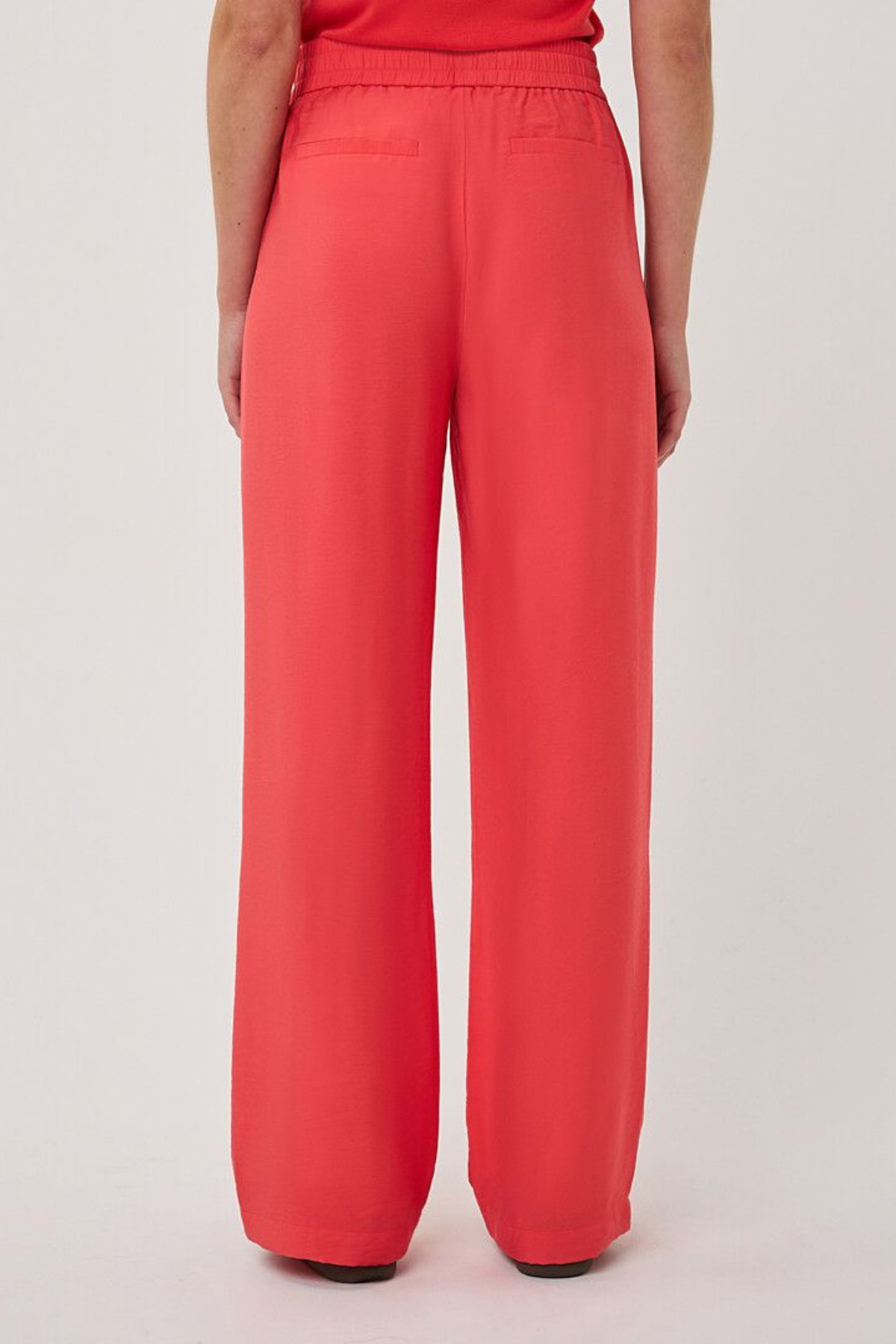 Person wearing bright red wide-leg pants on a light gray background