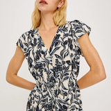 Woman wearing a black and white floral dress against a plain background