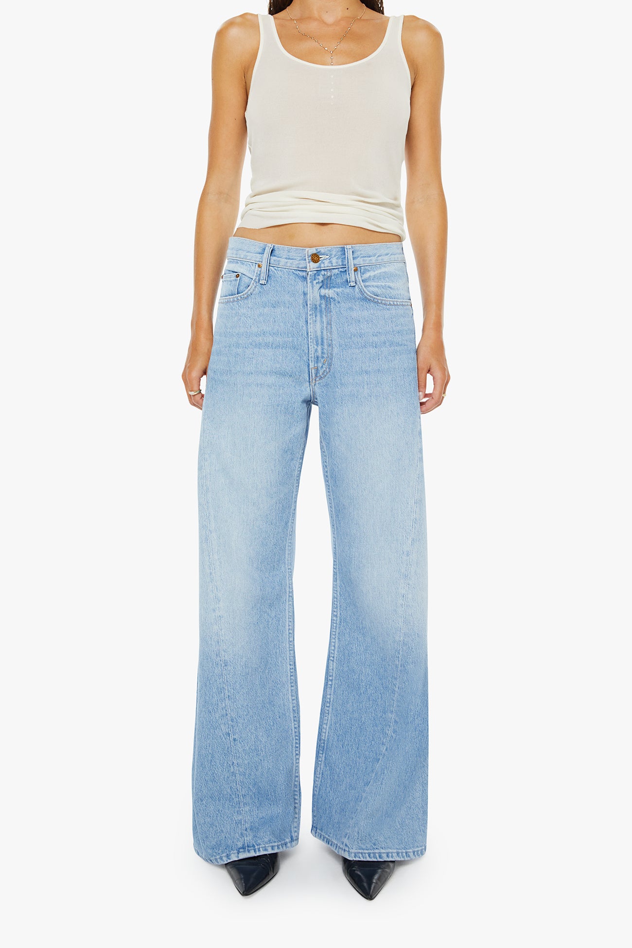 Person wearing light blue jeans and a white tank top on a white background