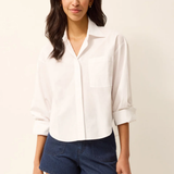 Woman wearing a white shirt and blue shorts on a plain background