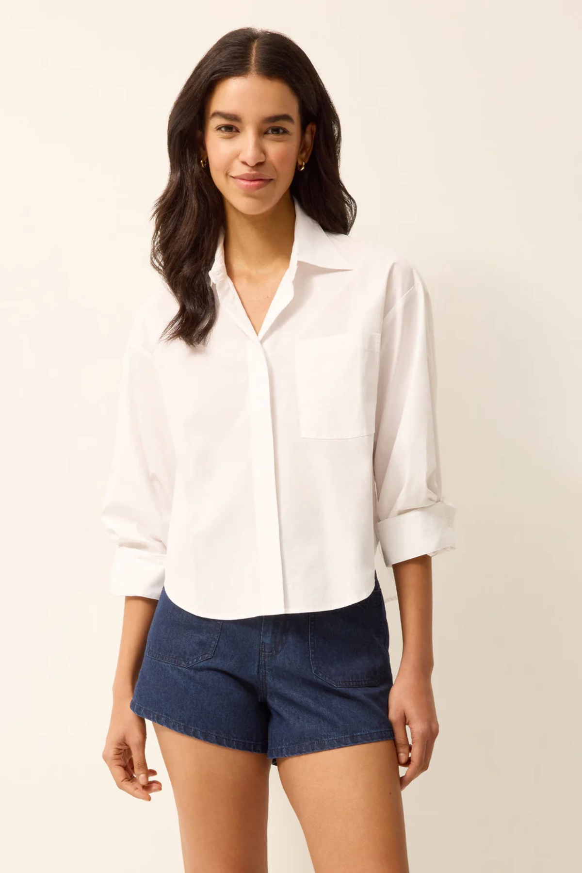 Woman wearing a white shirt and blue shorts on a plain background