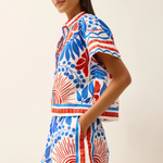 Woman wearing a colorful patterned dress on a plain background