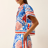 Woman wearing a colorful patterned dress on a plain background