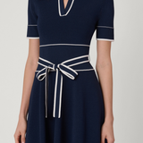 Navy blue dress with white trim on a plain background