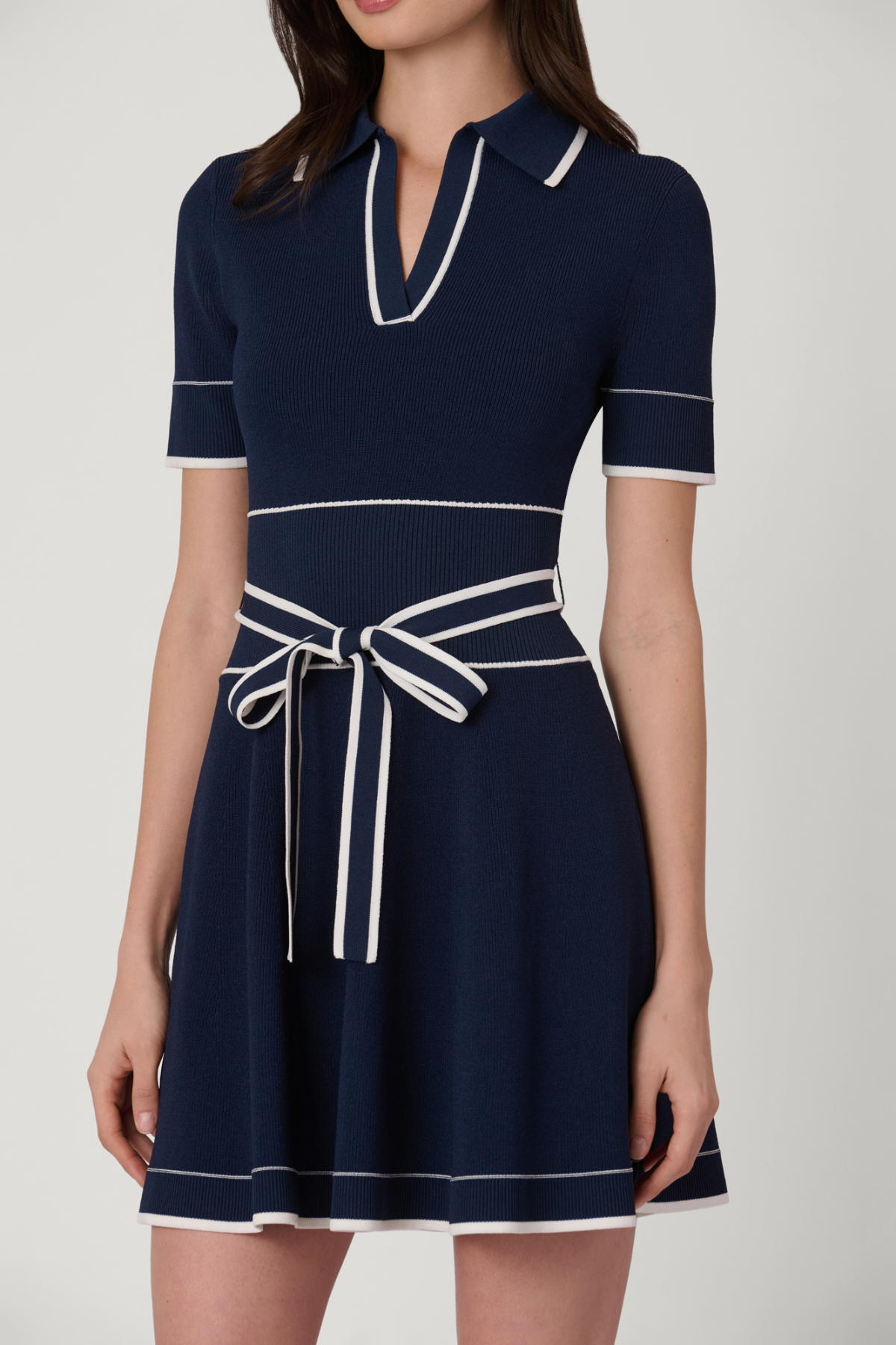 Navy blue dress with white trim on a plain background