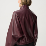 Person wearing a maroon leather jacket on a white background